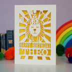 A laser cut lion birthday card, personalised with a name and age and featuring a lion in a party hat