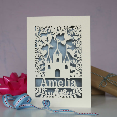 A pretty birthday card with a castle, leaves, hearts and floral papercut design. Name shows at the bottom and age is inside a heart. Card is cream and silver. - A5 / Silver