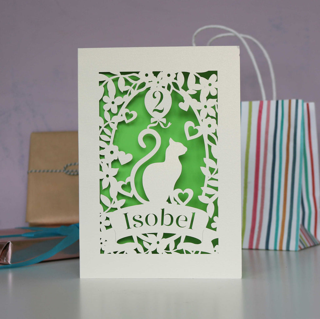 Fresh bright green and cream laser cutout card showing a cat and a balloon. Personalise with their name and age.