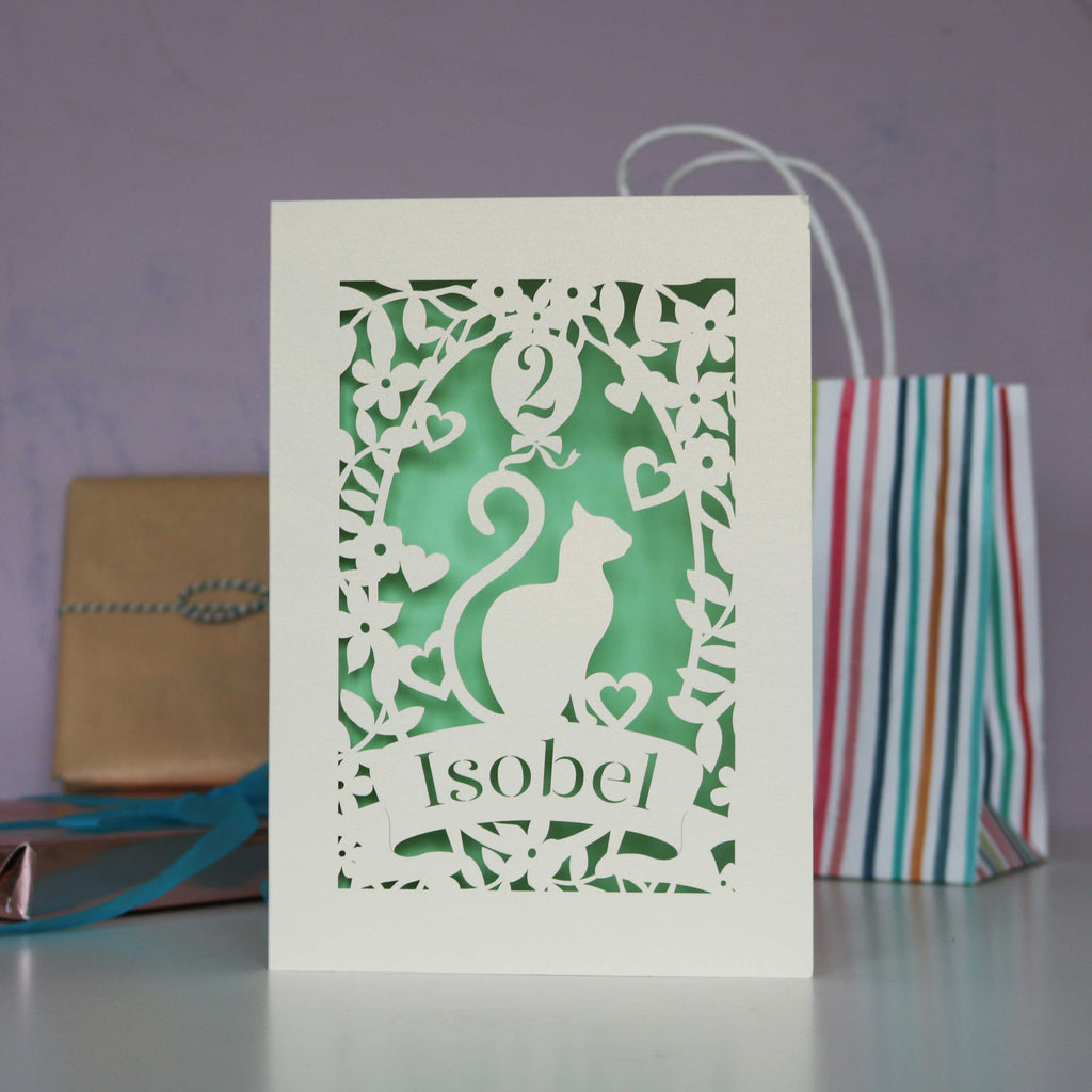 Cat lady birthday card, showing a cat with a balloon. Age can be put in the balloon. Personalise with a name and age. Laser cut from cream card and finished off with a pale green background.
