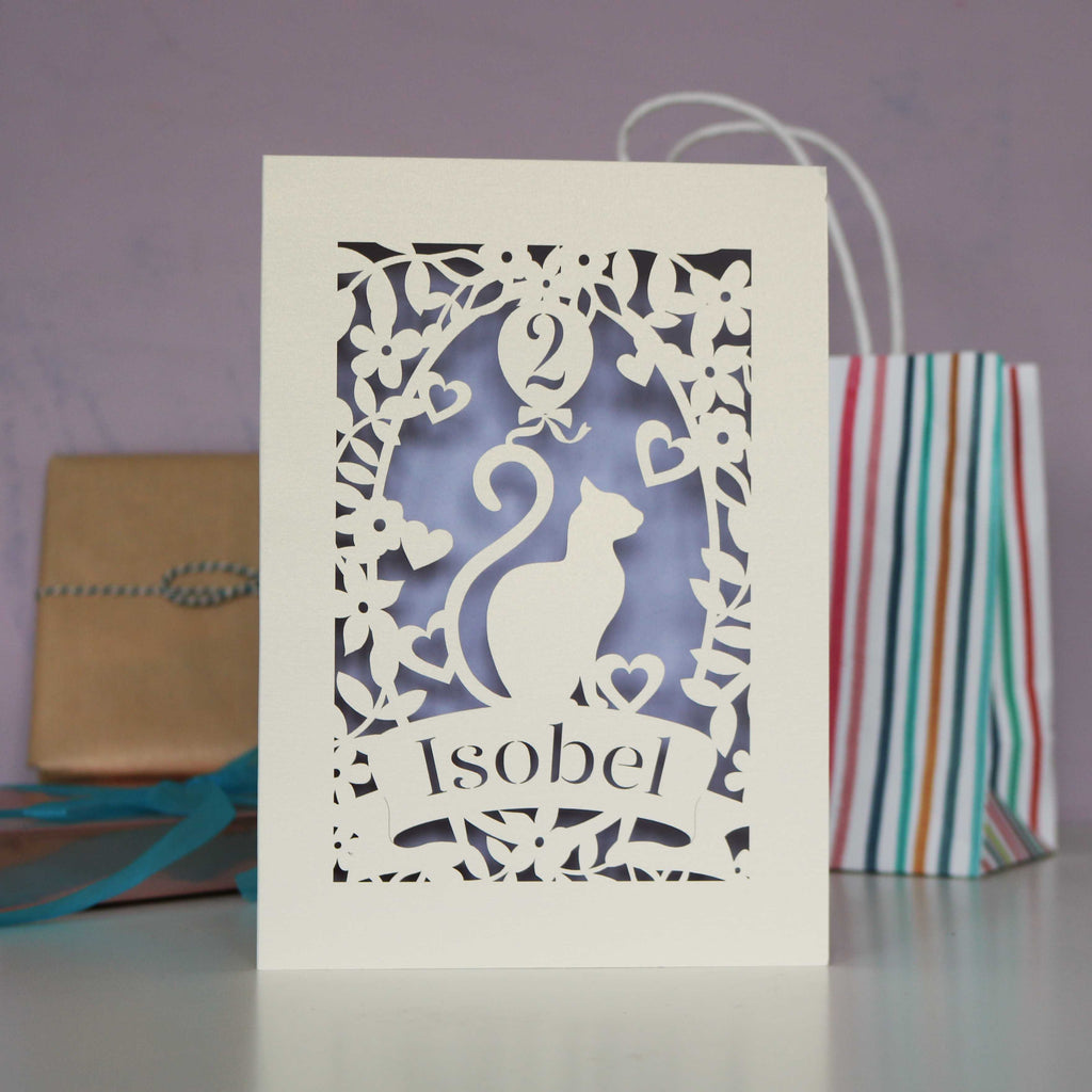 Pretty cat personalised laser cut card. Shows cut from cream card and  lilac insert paper. Personalise with an age in the balloon and a name in the banner.