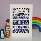 A laser cut card with "Jacob, Brilliant Big Brother", on a desk with wooden toys
