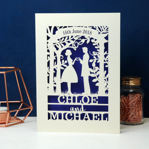 A laser cut engagement card that features the silhouettes of a couple, and is personalised with a date in a banner at the top and the names of the couple over three lines of text at the bottom - A6 (small) / Infra Violet