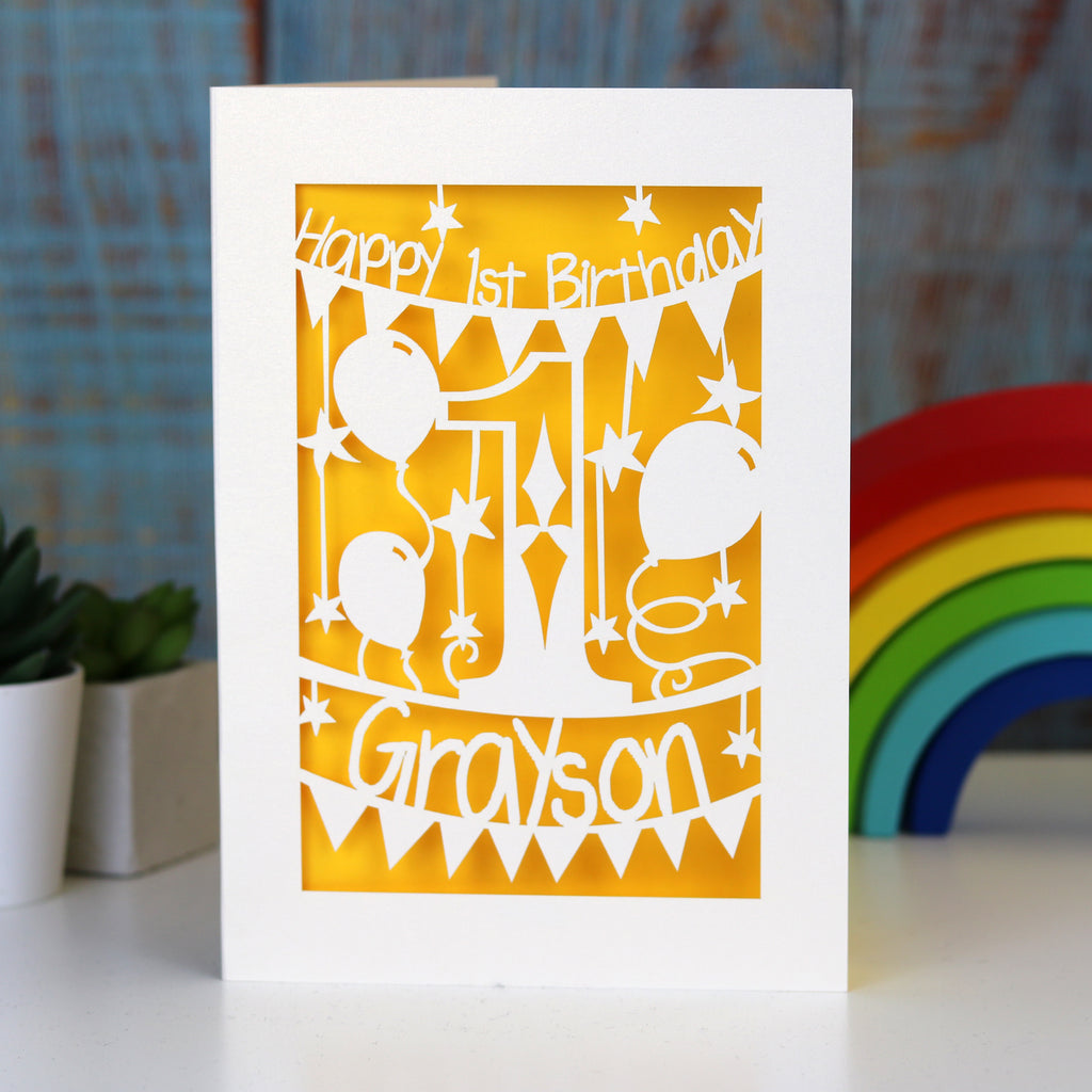 A laser cut card for a first birthday. This card is cream with a sunshine yellow paper insert. 