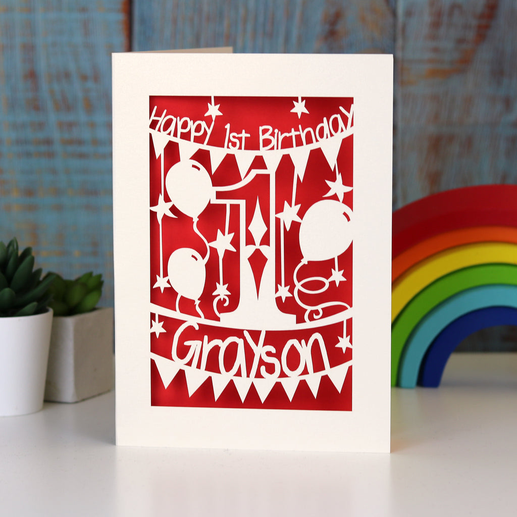 A Happy First Birthday laser cut card with stars and balloons. Card is personalised with a name.