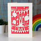 A coral pink 1st birthday card for grandchild. Happy 1st Birthday is written at the top and a name is at the bottom.