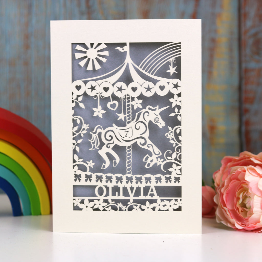 A cream and silver birthday card, personalised and laser cut. Card shows a carousel horse, flowers and stars