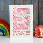 A cream and light pink girls birthday card with a carousel horse, a name and an age.