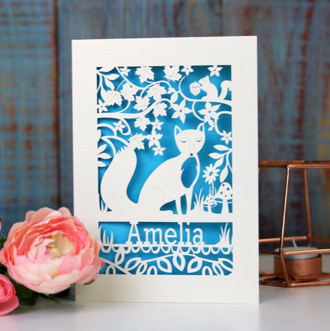 A laser cut card for birthdays. This card has a fox and a name and flower and leaf shapes. Card is cut away to reveal a blue paper behind - A5 (large) / Peacock Blue