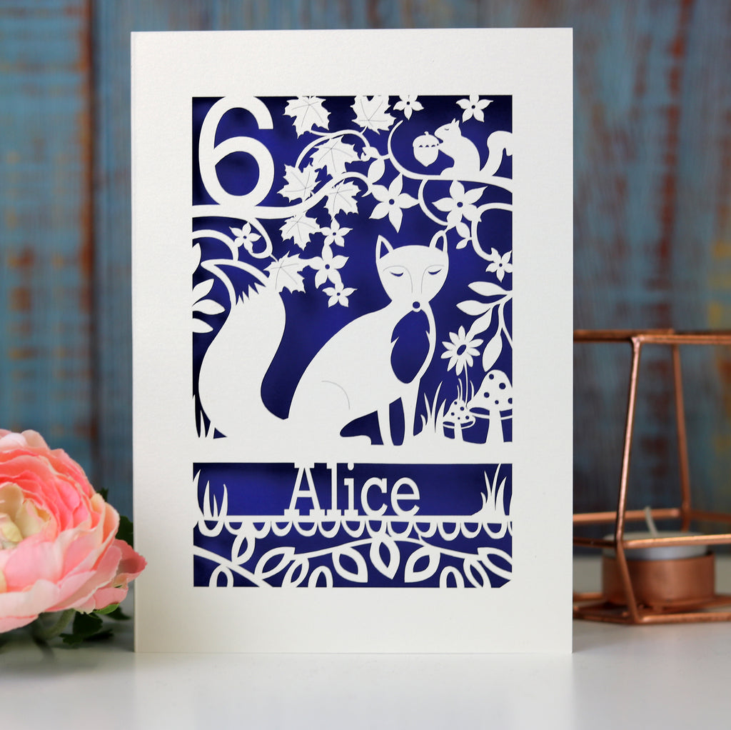 Personalised child's birthday card, laser cut from cream card with a violet paper insert. Card has a fox, tiny squirrel and toadstool details.