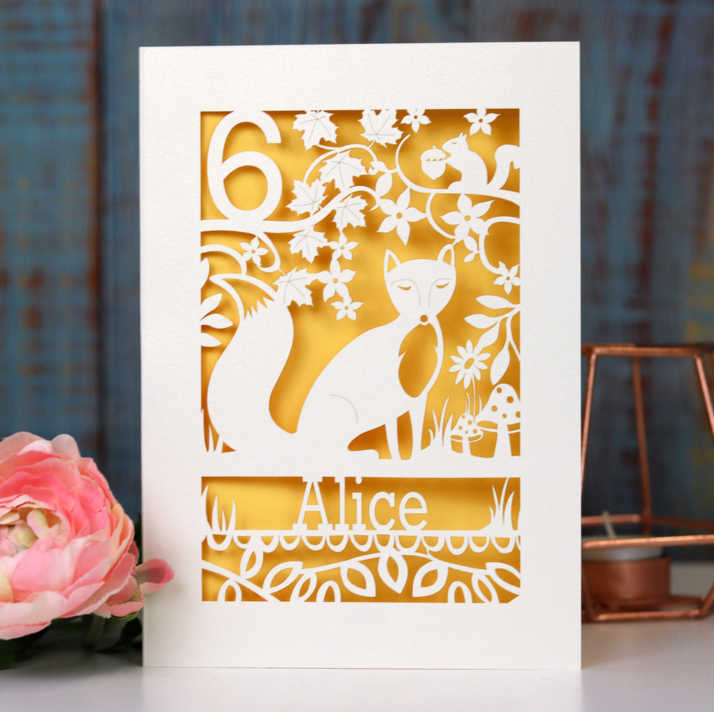 A birthday card for a child. There is a fox, surrounded by woodland details and a name and age. Card is laser cut. 