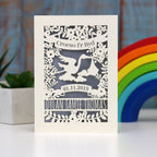 Welsh new baby welcome to the world papercut card, Croeso i'r Byd.  Personalise with baby's name and date of birth. Showing a stork delivering a baby bundle, with space for baby's name and date of birth. Lasercut from cream card and finished with a silver insert paper.