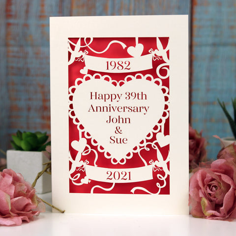 A laser cut card for a wedding anniversary with years of wedding and anniversary in banners and the names of the couple in a heart in the centre.  - A6 (small) / Bright Red