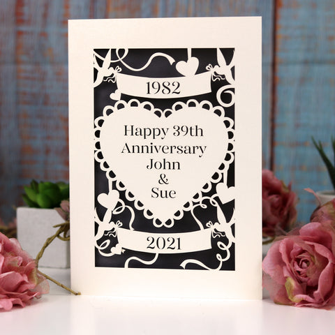 A laser cut card for wedding anniversaries. Personalised with the years of marriage and anniversary, and the first names of the couple. Design features birds holding banners, ribbons and a heart shape in the centre - A6 (small) / Urban grey