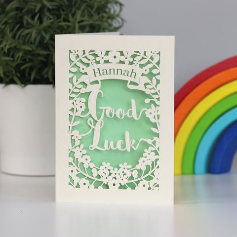 Pretty laser cut Good Luck card cut from cream card and finished with a pale green insert paper. Shows  the words "Good Luck" cut from the centre, surrounded with flowers and a banner above for the peronalisation. - A5 / Light Green