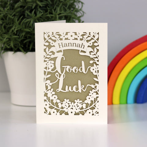 Very elegant papercut Good Luck personalised card. Cut from cream card and finished with a beautiful gold insert paper. Shows the words Good Luck, flowers and a banner for the name. - A5 / Gold Leaf