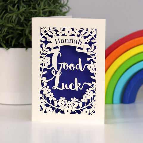 Personalised Good Luck paper cut card, lasercut from cream card and finished with a dark blue insert paper.  Shows a banner for the personalisation above the words "Good Luck." - A5 / Infra Violet