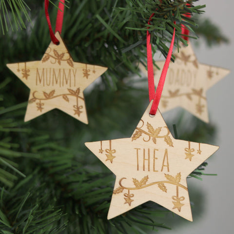 Three small star personalised Christmas decorations hanging on a tree.  - 