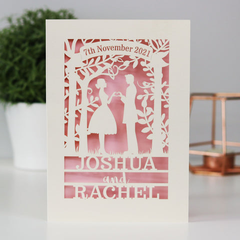 A personalised cut out wedding card that features the silhouettes of a couple, and is personalised with a date in a banner at the top and the names of the couple over three lines of text at the bottom - A6 (small) / Candy Pink