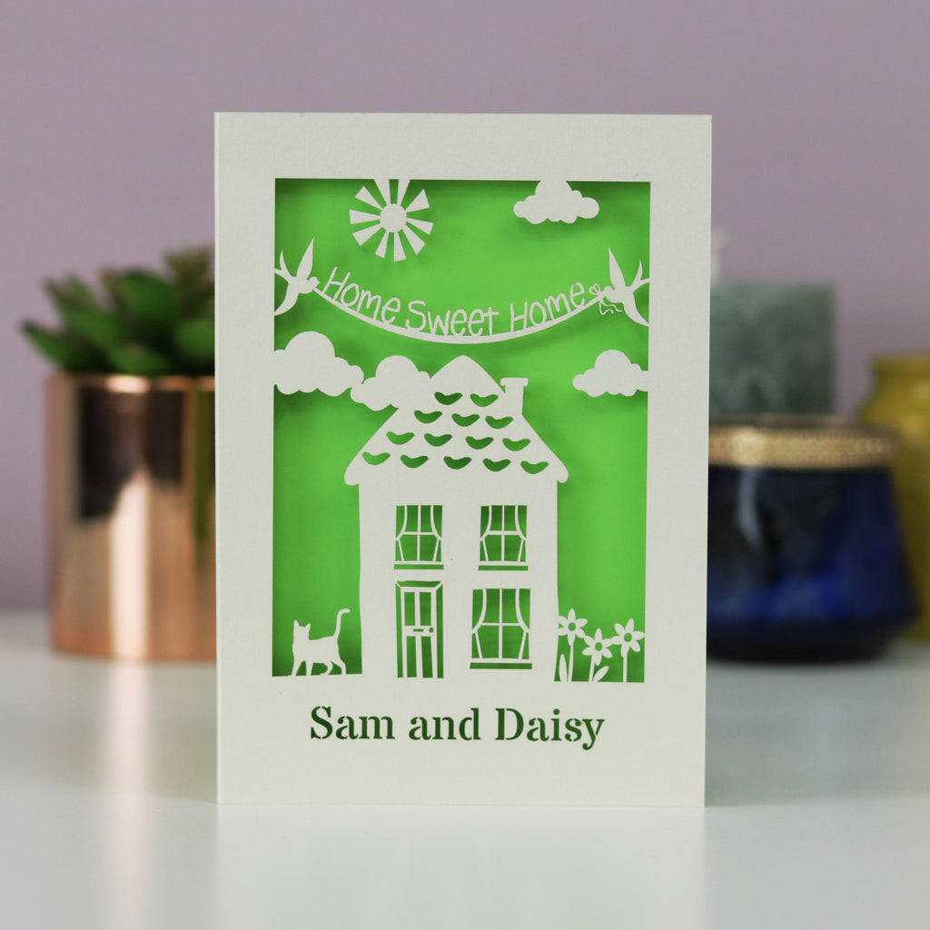 A unique personalised new home card with a house, cat, flowers, the words "home sweet home" and the recipient's name