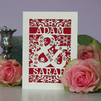 A cream and red laser cut wedding card with "Adam & Sarah" flowers and leaves.