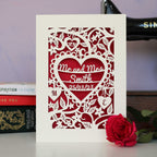 A floral personalised wedding card laser cut in the UK from cream card with red backing. Personalised with names and date in a heart shape.