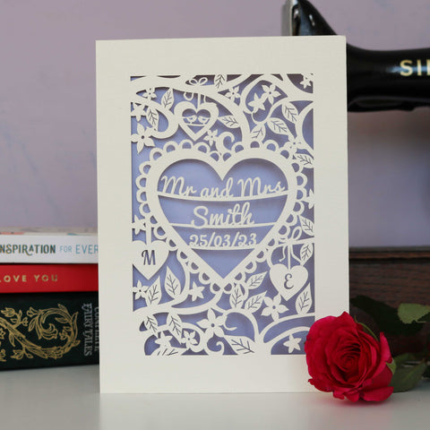 A personalised papercut wedding card in cream and lilac. Card shows Mr and Mrs Smith inside a heart with the date of the wedding. Two smaller hearts show the initials of the couple. - A6 / Lilac