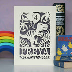 Personalised birthday cards for dinosaur fans. Image shows a laser cut dinosaur holding balloons and is personalised with an age and name.