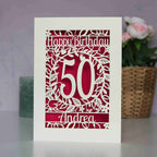 A laser cut birthday card for friends or family. Personalised with an age in the centre and Happy Birthday and a name. This image shows cream card and shocking pink paper.