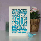 A laser cut birthday card personalised with an age and name. Blue paper shows through the cut design.