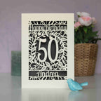 A cream and grey laser cut birthday card with flowers and leaf shapes. Card says "Happy Birthday, 50, Andrea"