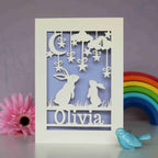 Personalised special birthday cards for kids. A cream card with a parent bunny and baby bunny silhouette booking up at the night sky, personalised with a name and age. Cream card with a lilac paper insert behind the cut away card.