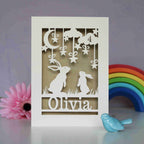 A cream and gold papercut birthday card with rabbits looking up at the moon and stars