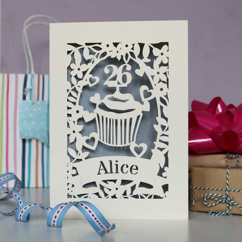 Elegant silver and cream personalised  birthday card. Shows a cupcake with an age topper, leaves, flowers and hearts all laser cut from cream card. Personalise with age and a name. - 