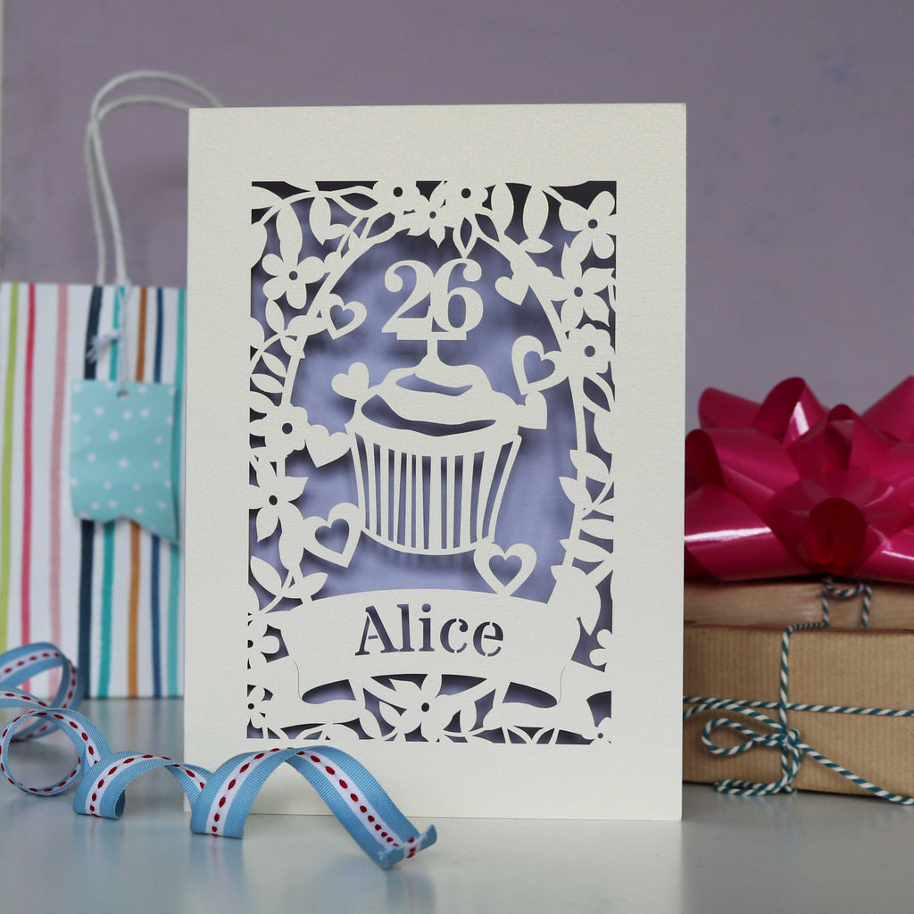 Laser cut personalised cupcake birthday card.  Cupcake has a topper which can be personalised to the birthday person's age, with their name underneath. Cut from cream card with a lilac insert paper.