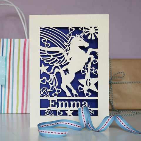 Personalised unicorn birthday cards. This image shows a laser cut card with a unicorn surrounded by hearts, stars and a rainbow. - A5 / Infra Violet