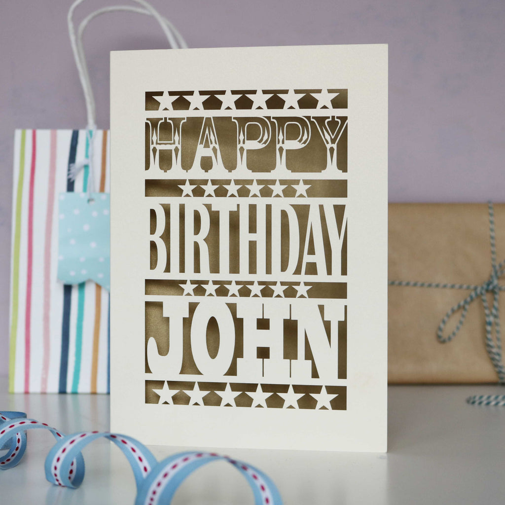 Cream laser cut card for birthdays, saying happy birthday with a name, and gold leaf paper behind cut out card