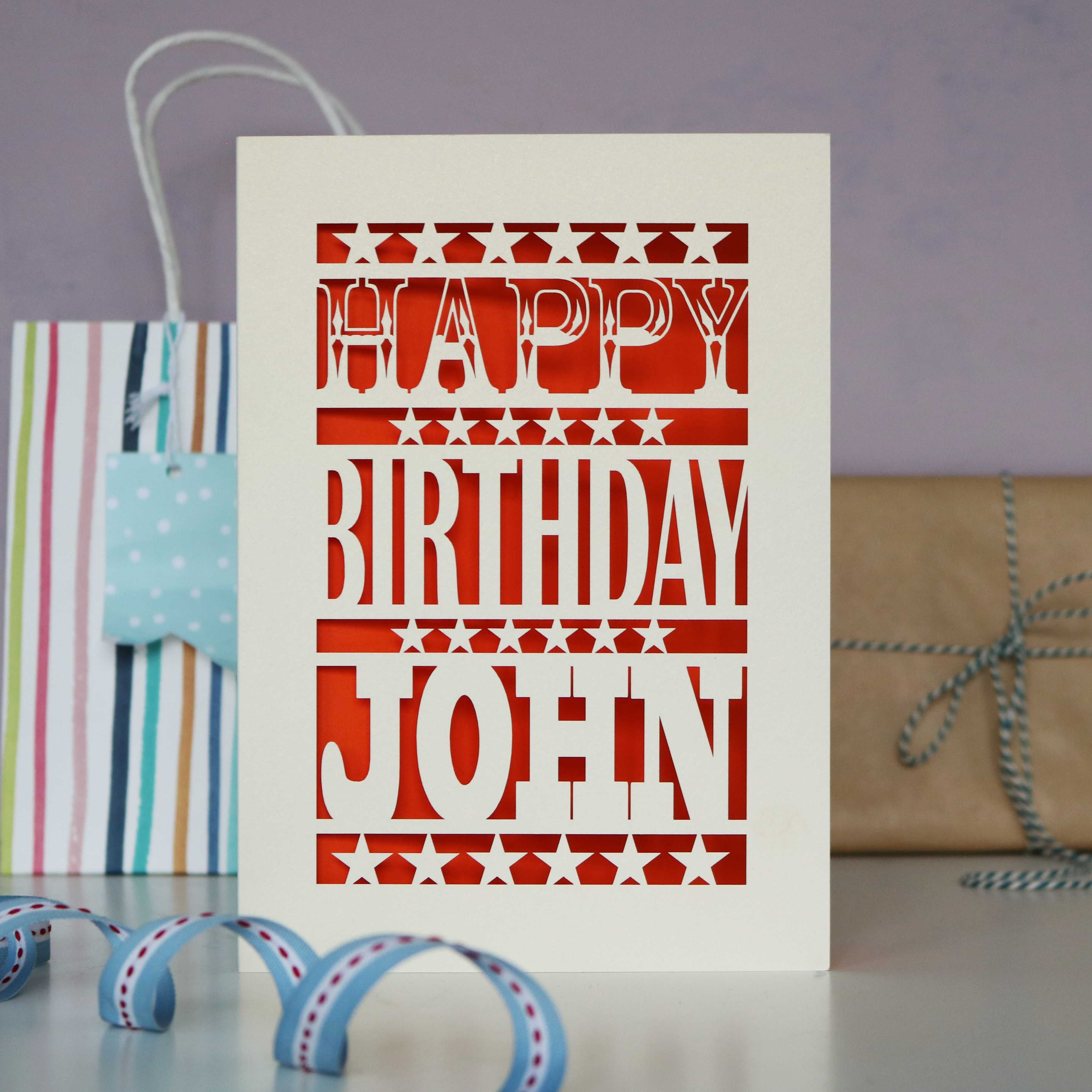 A cream birthday card laser cut to say happy birthday with a name underneath.