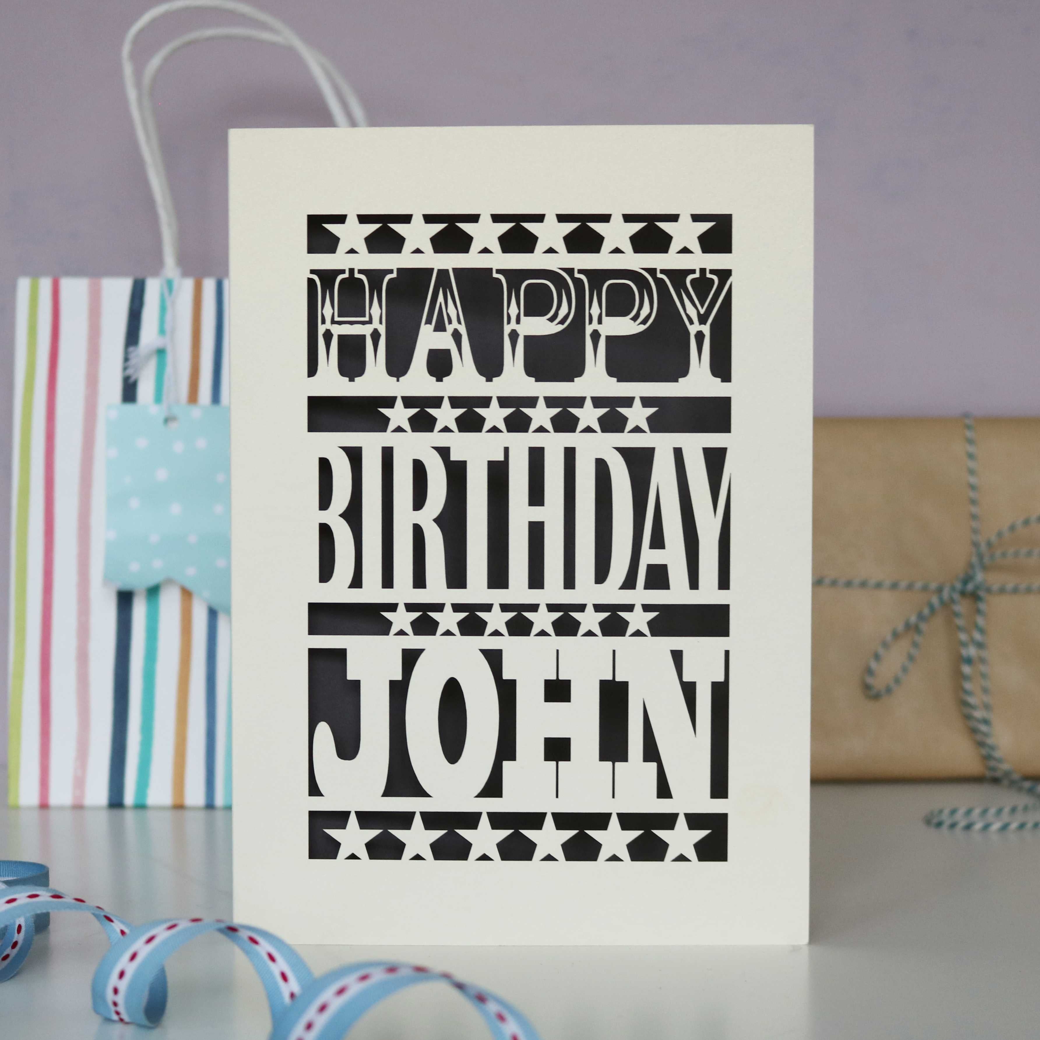 A man's birthday card, personalised with a name and laser cut from cream and dark grey.