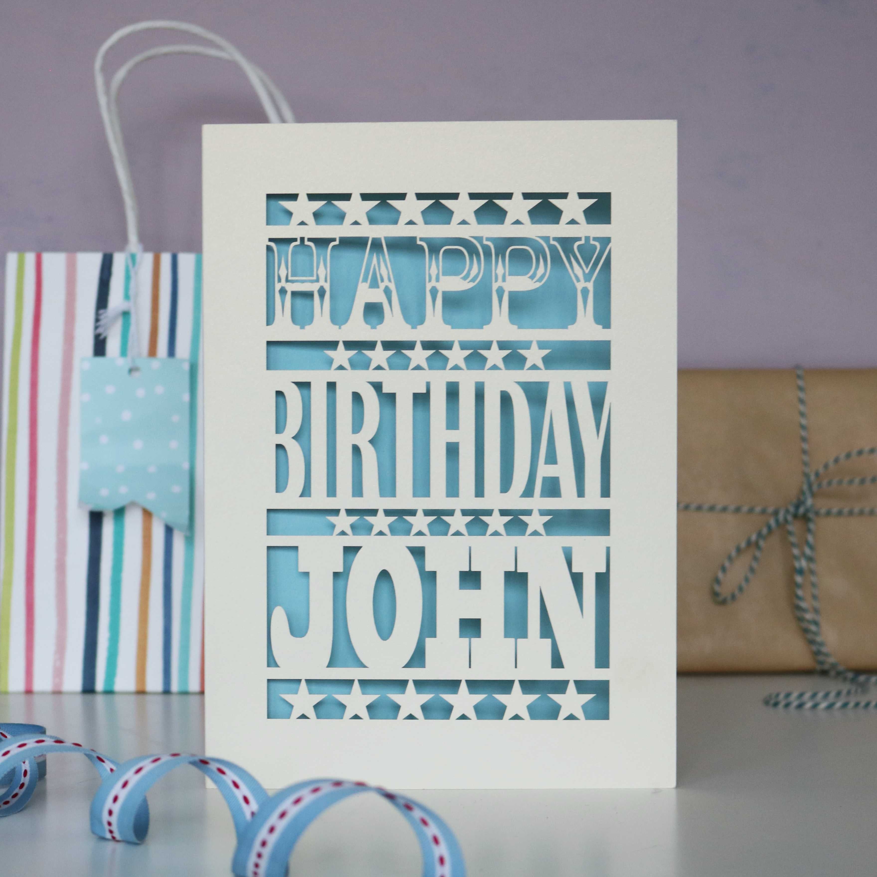 Personalised paper cut birthday card for him. Cream and light blue, personalised with a name. 