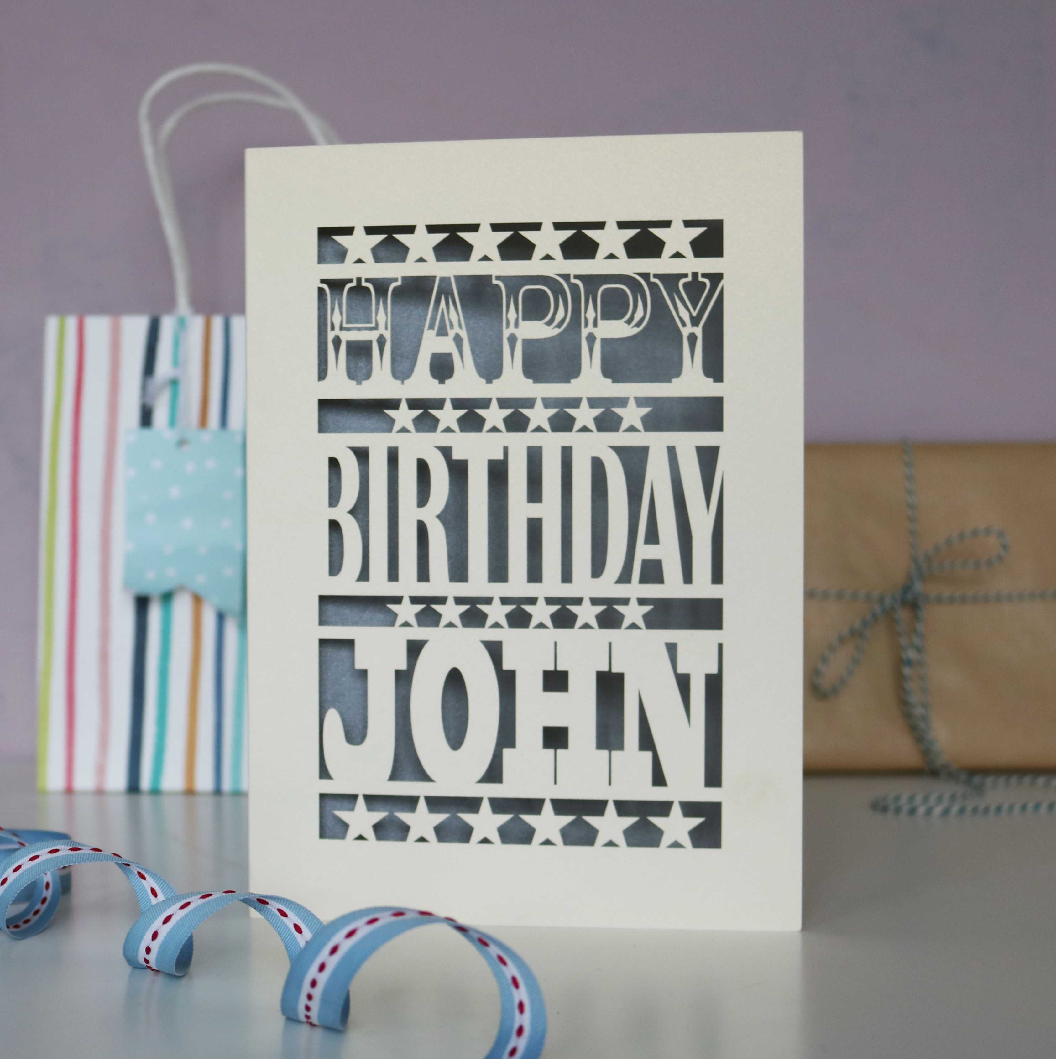 A personalised laser cut birthday card for a man. Stars and bold chunky text that says "Happy Birthday Daniel." Card is cream and silver.