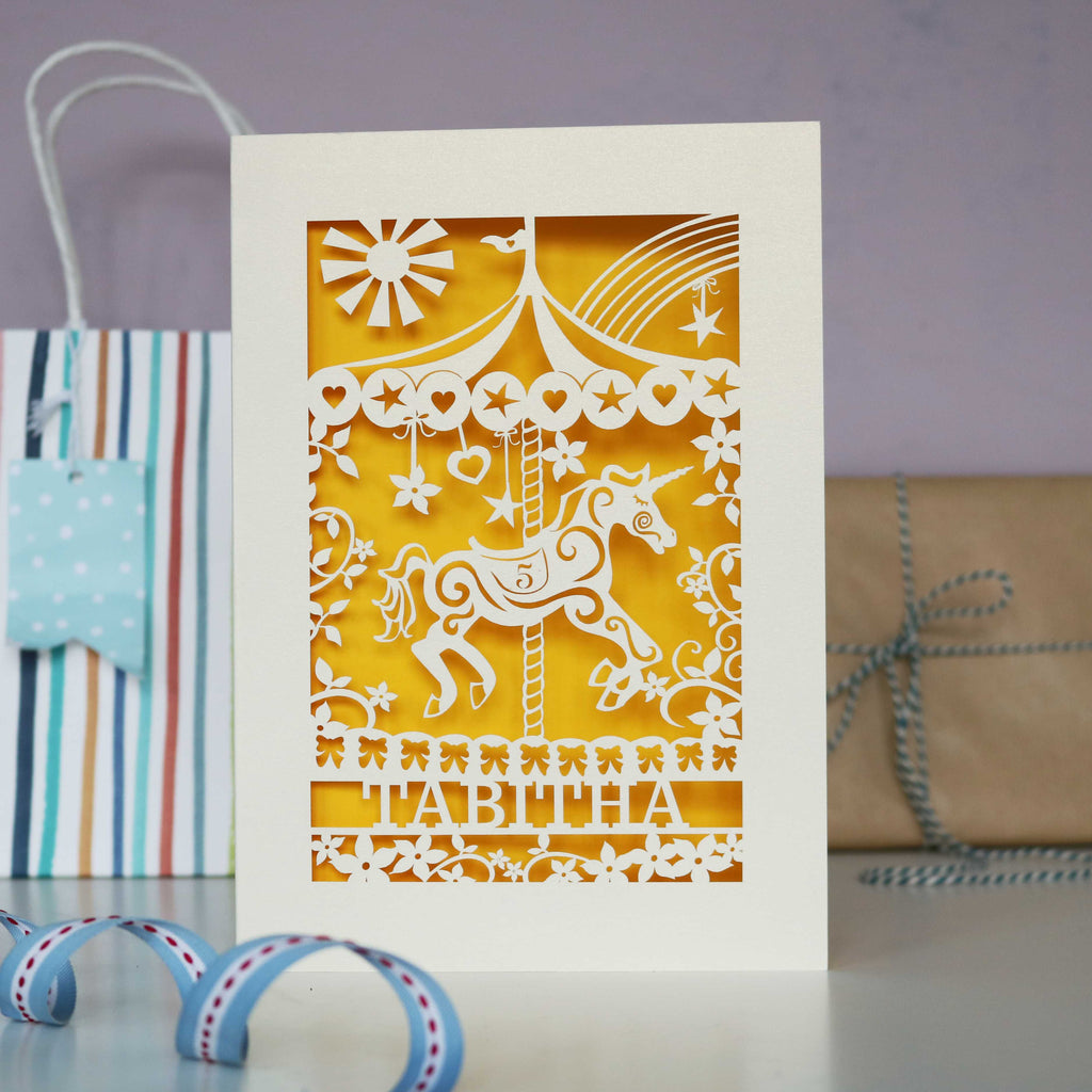 A cream and yellow laser cut birthday card, personalised with child's name and age. 