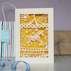 A cream and yellow laser cut birthday card, personalised with child's name and age. 