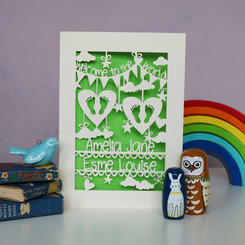 Beautiful welcome to the world card for twins. Cut from cream card with a bright green insert paper and showing  two sets of feet in two heart with clouds, stars and hearts. Two lines for the babies names across the bottom. - A5 / Bright Green