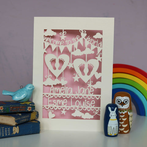 Pretty pale pink insert paper with cream card, personalised twins card. Lines to add the babies names with hearts above with tiny feet cutouts. Lots of clouds, stars and hearts with "Welcome to the world" on bunting across the top. - A5 / Candy Pink
