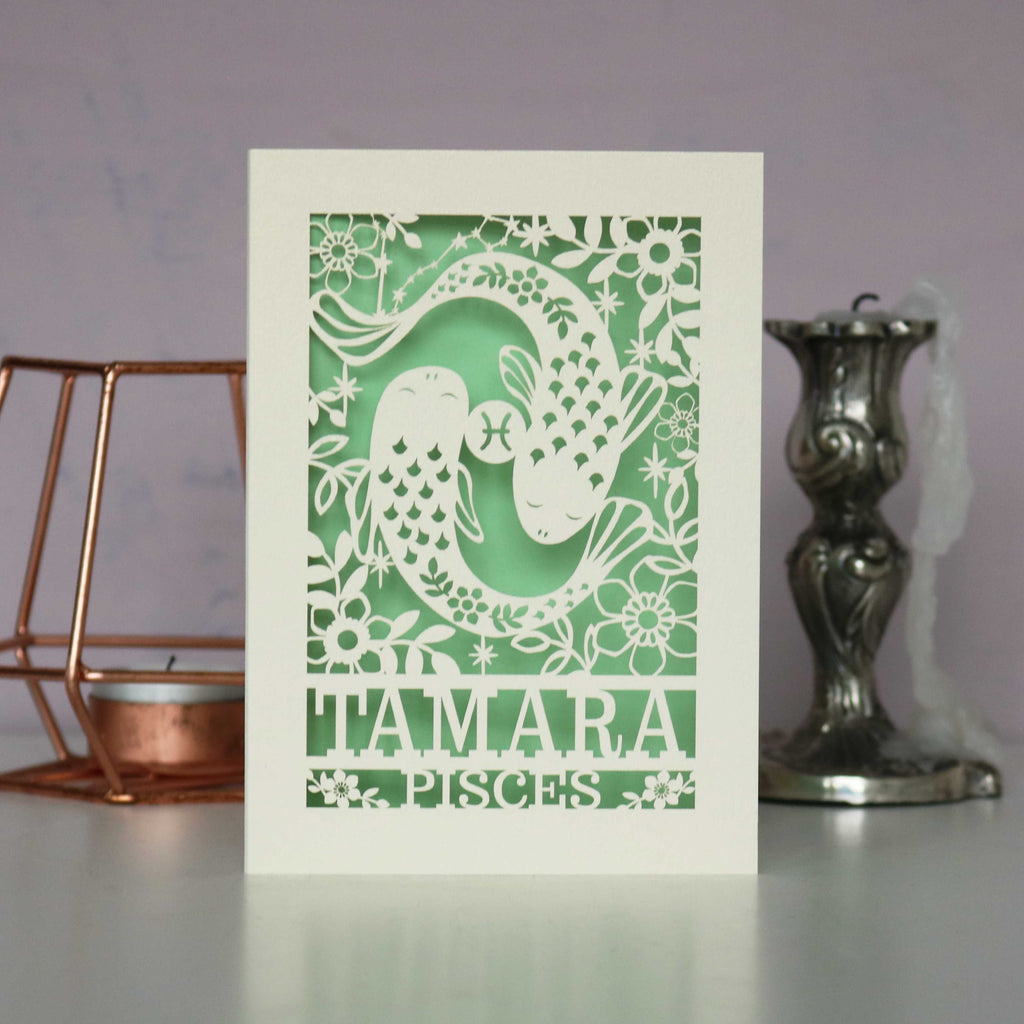 A personalised birthday card with a papercut design featuring the Pisces constellation and a fish symbol.