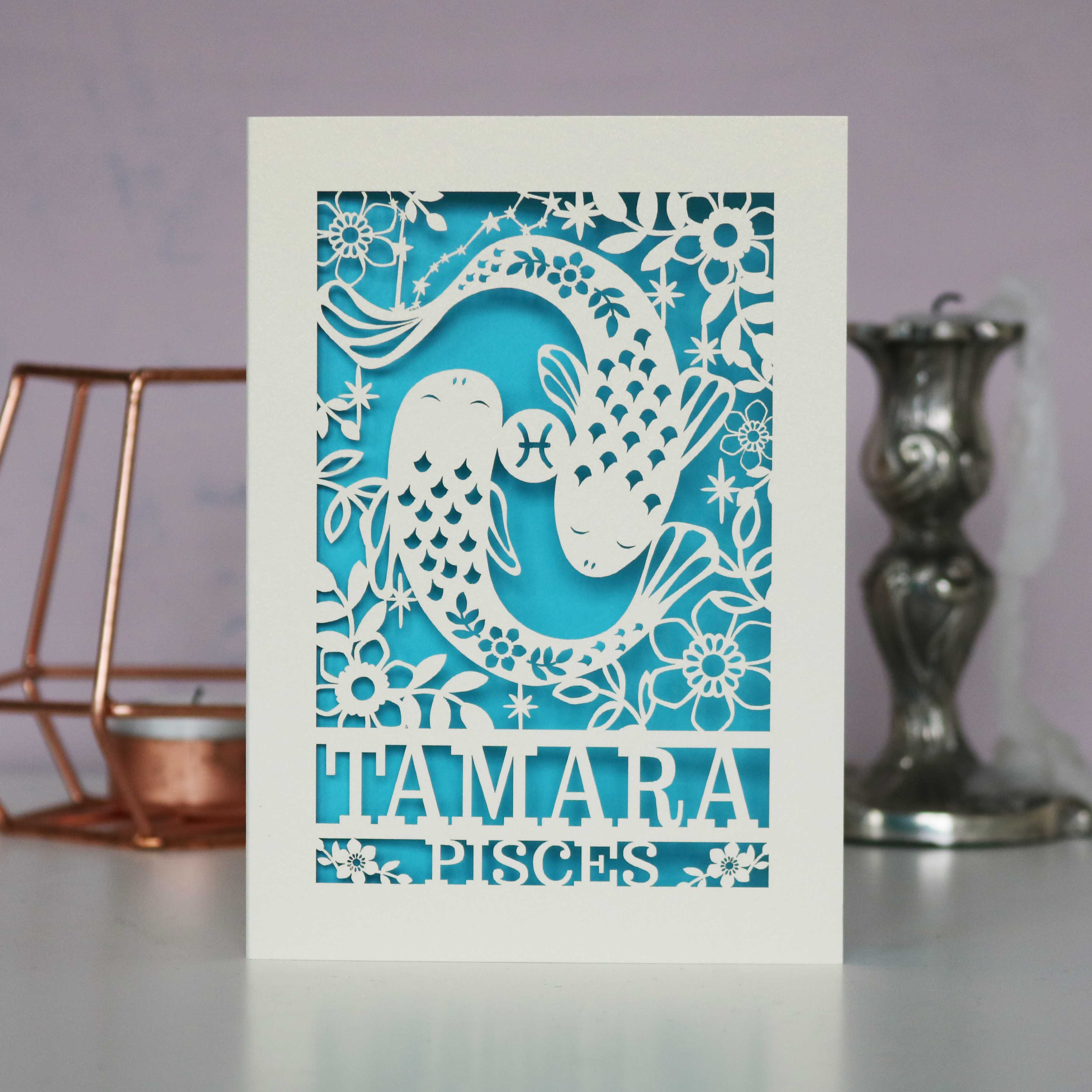 A personalised birthday card with a papercut design featuring the Pisces constellation and a fish symbol.