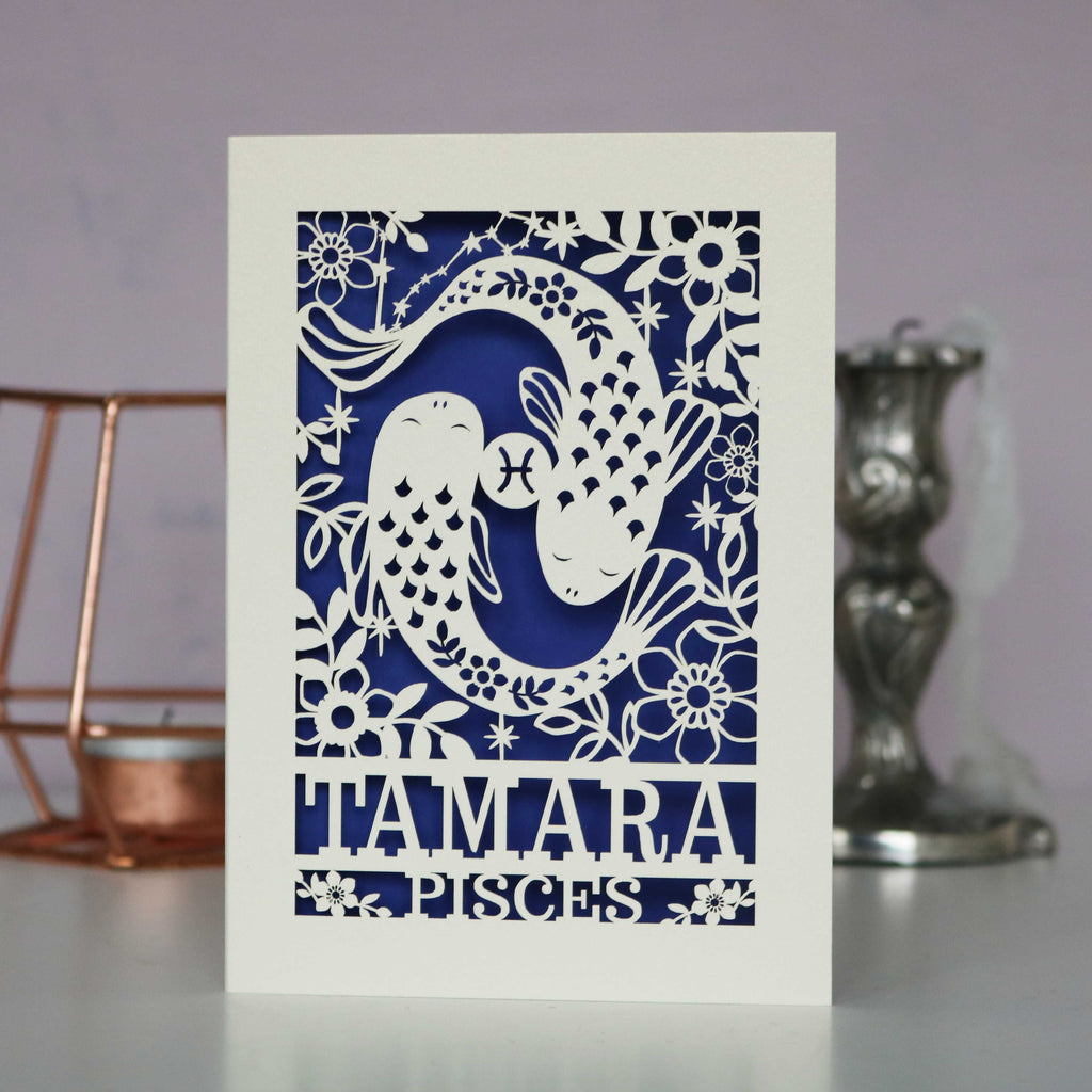 A personalised birthday card with a papercut design featuring the Pisces constellation and a fish symbol.