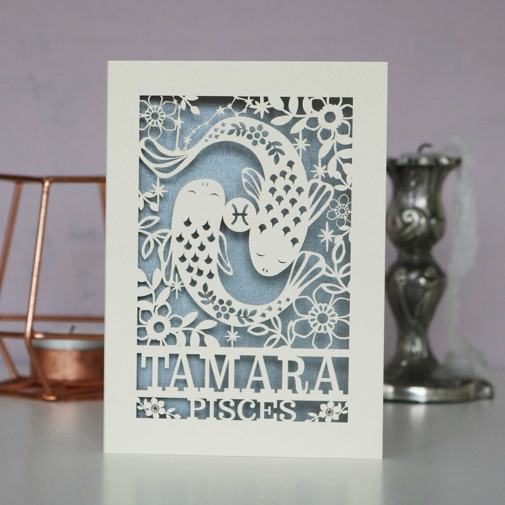 A personalised laser cut Pisces birthday card with a papercut design featuring the Pisces constellation and a fish symbol.
