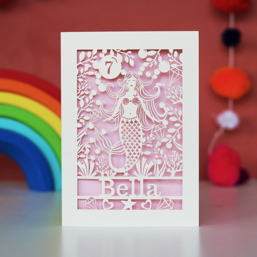 A cream and candy pink birthday card for her, featuring a laser cut mermaid, a name and age.